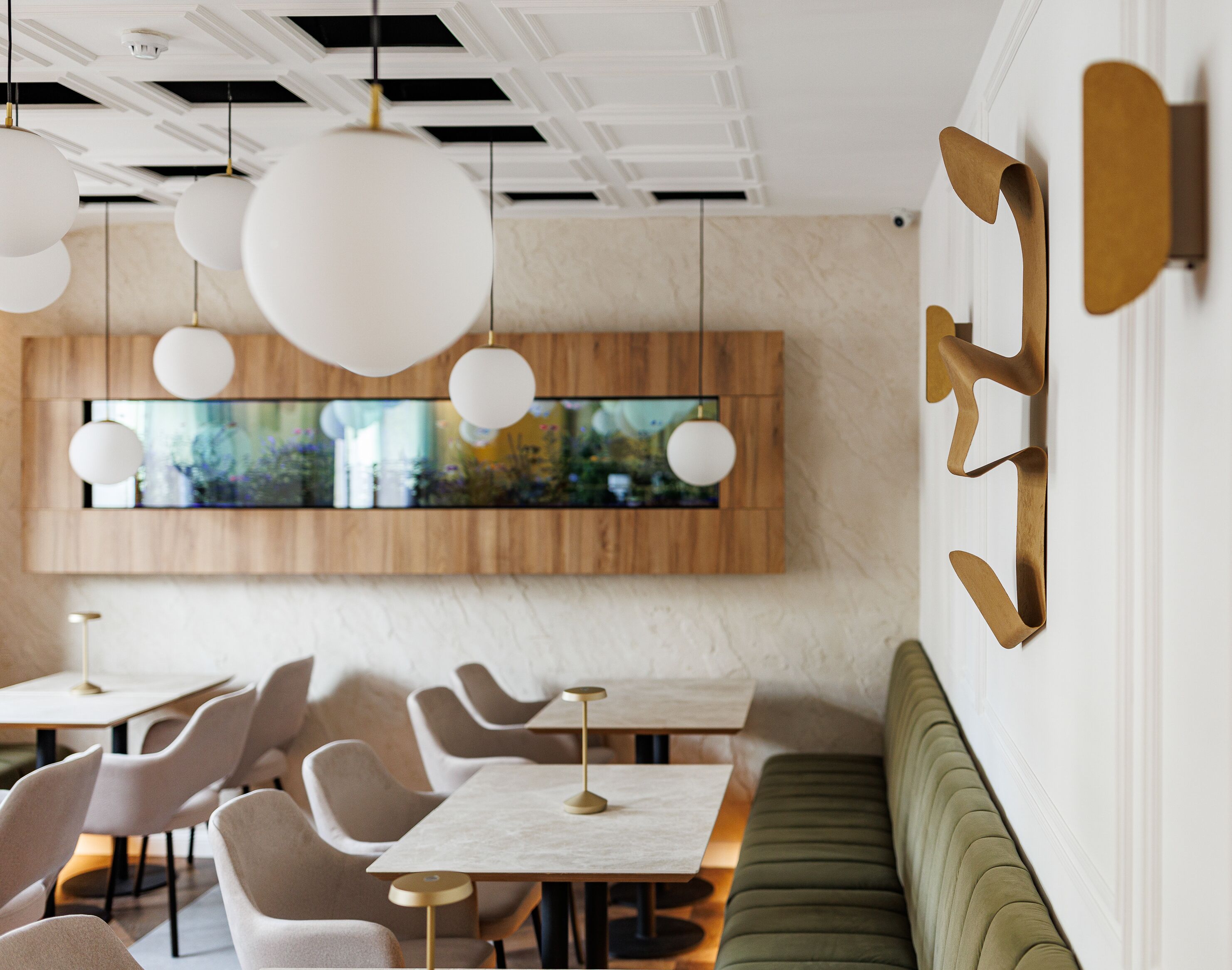 Un comedor moderno con mesas redondas, sillas acolchadas e iluminación colgante.