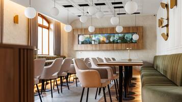 A modern dining area with a long table, multiple chairs, and a sofa.