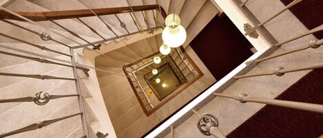 Un escalier en colimaçon avec un espace central ouvert et un lustre.