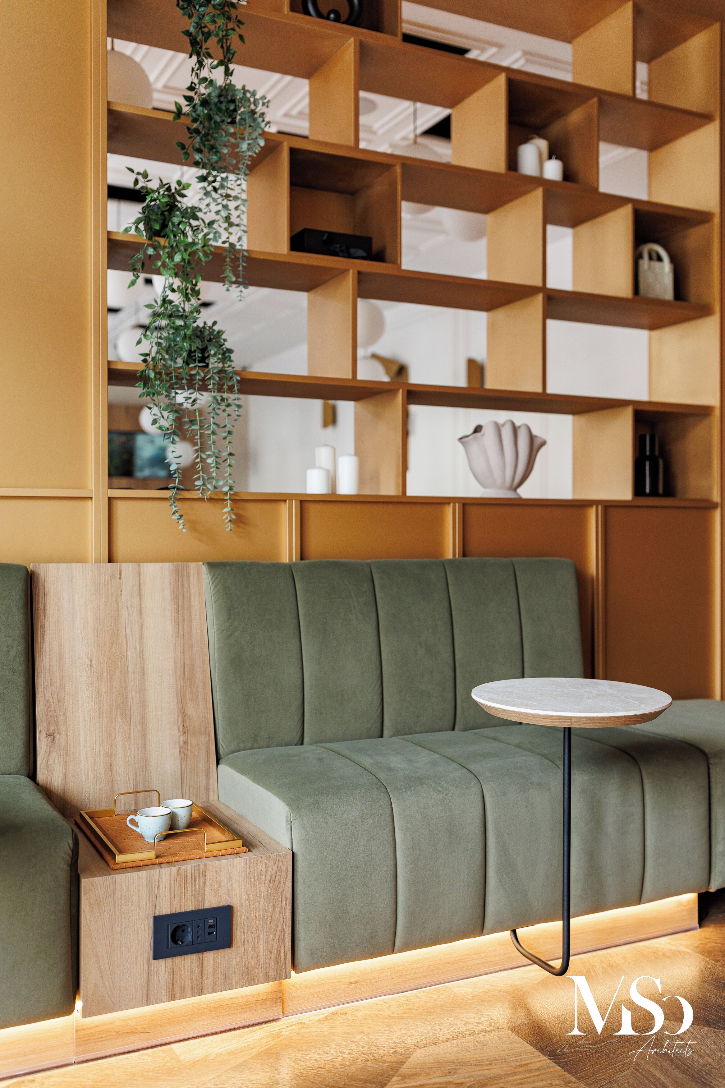 A modern living room with a green sofa, a wooden side table with a tray, and a round white table.