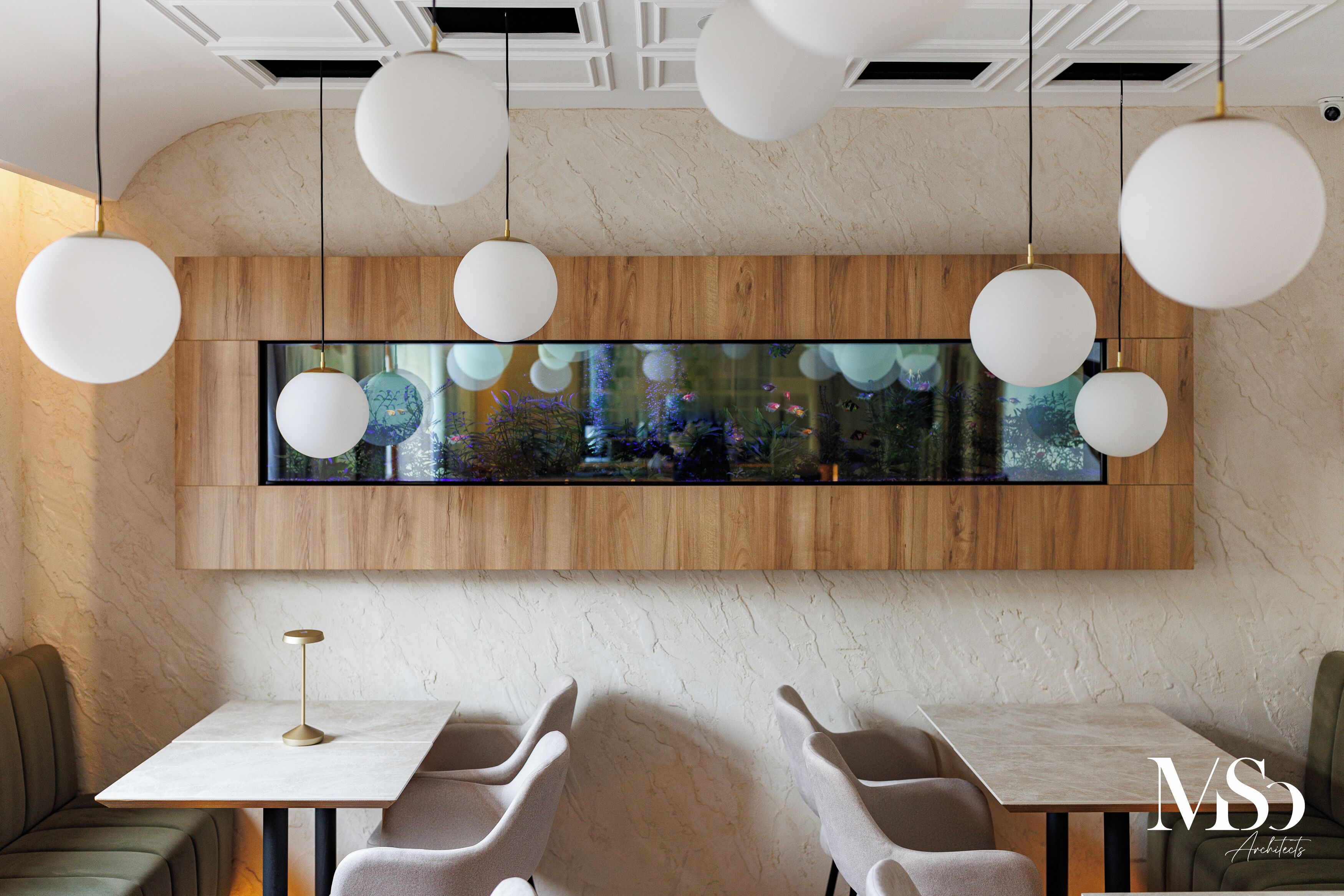Un intérieur moderne agrémenté d’un grand aquarium, de lambris en bois et de meubles contemporains.