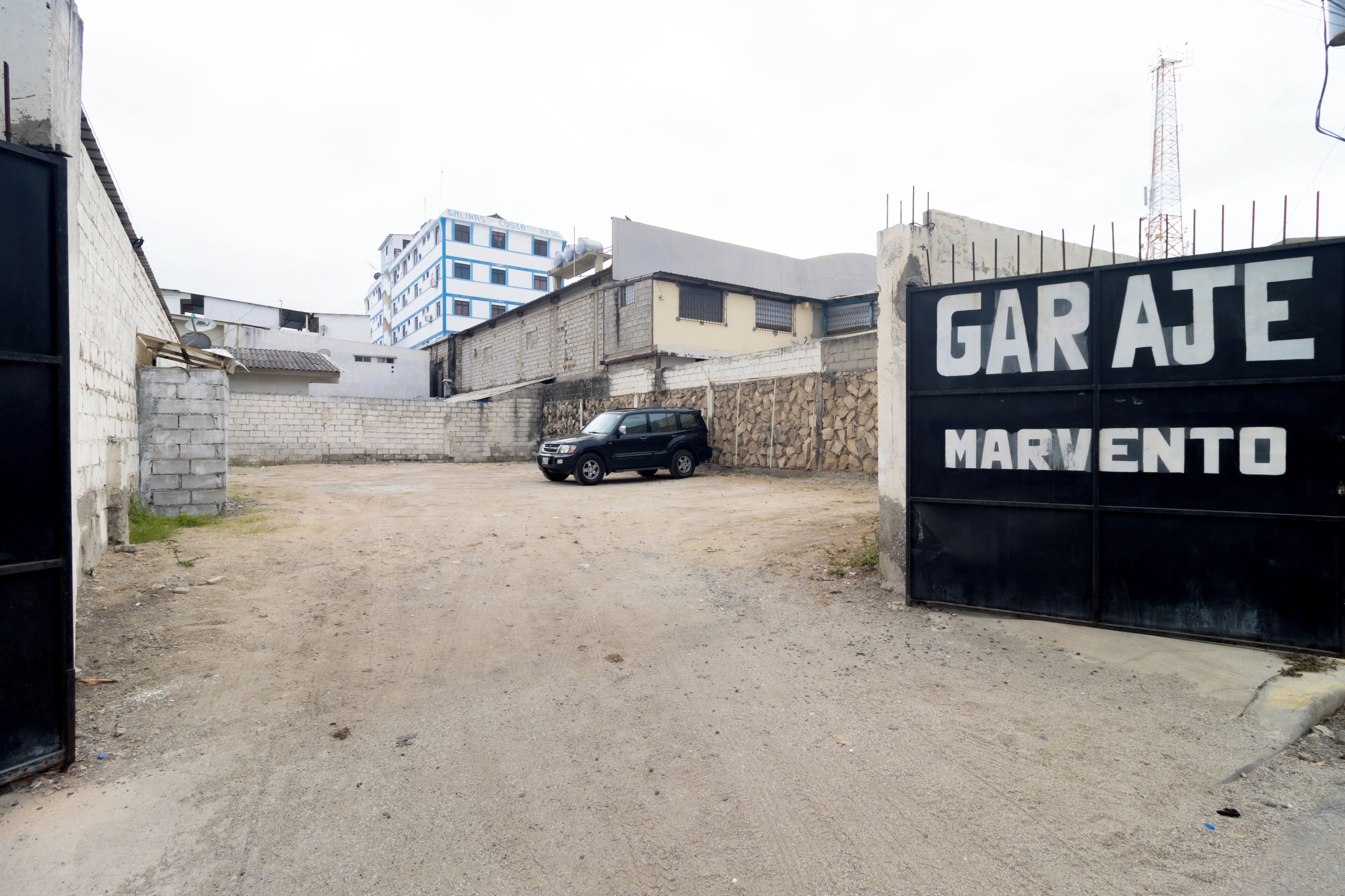 Une zone délimitée par une barrière, sur laquelle on peut lire l’inscription « GARAGE MARVENTO », et devant laquelle est garé un SUV noir.