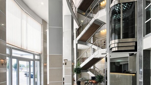 A spacious lobby with a high ceiling, multiple floors, and a central staircase. - Garni Hotel Zeder (Belgrade)