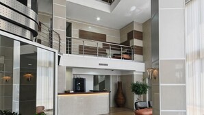 A spacious lobby with a high ceiling, a reception desk, and a staircase leading to an upper level. - Garni Hotel Zeder (Belgrade)
