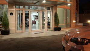 A modern hotel entrance with glass doors and a covered walkway. - Garni Hotel Zeder (Belgrade)
