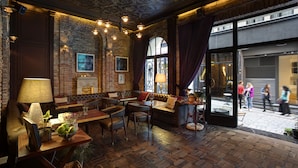 Un restaurant à l’ambiance chaleureuse, avec des murs en briques, des meubles en bois et un plafond orné de motifs.