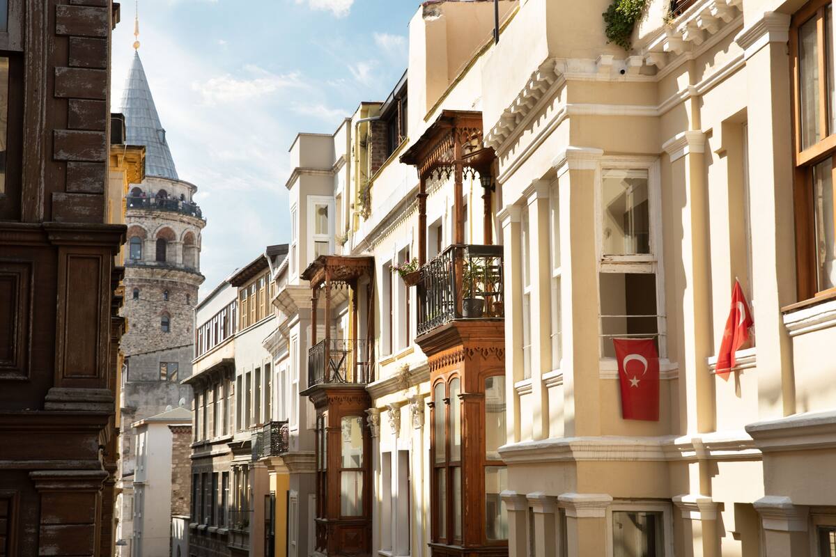 A row of historic buildings with ornate balconies and a prominent tower in the background.