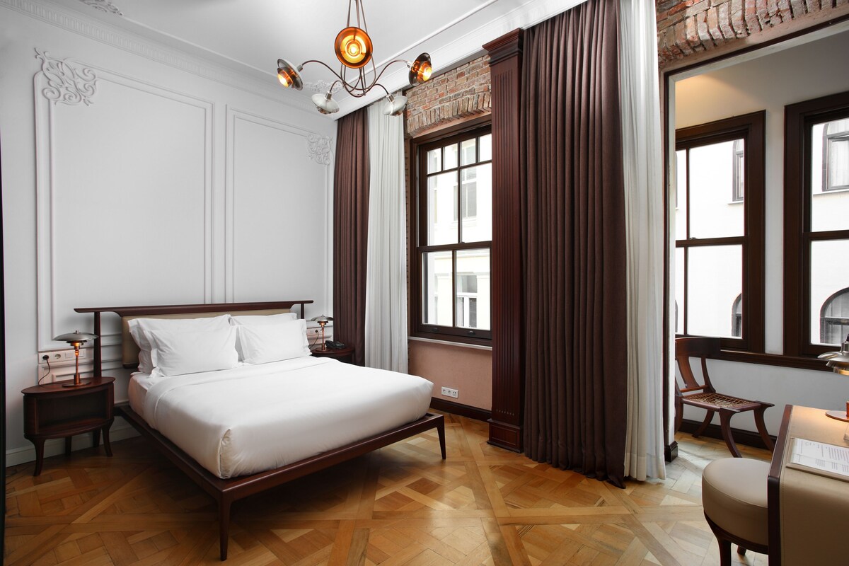 Una habitación de hotel con una cama de madera, una mesita de noche, un escritorio y una silla.