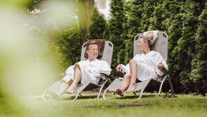 Two people sitting on lawn chairs in a garden. - Hotel Summerhof (Bad Griesbach im Rottal)