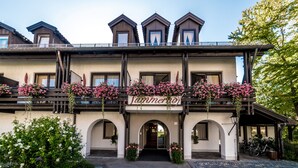 A hotel with a balcony adorned with flowers, a sign reading "Jummerhof," and a covered entrance. - Hotel Summerhof (Bad Griesbach im Rottal)