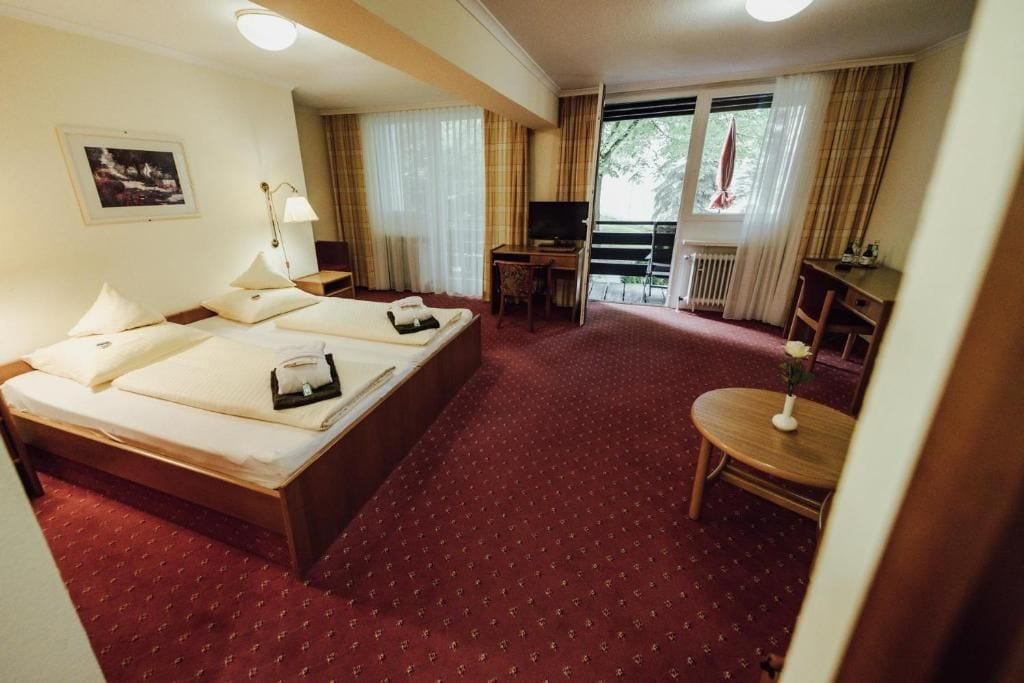 Una habitación de hotel con cama, escritorio, televisor y vistas al exterior.