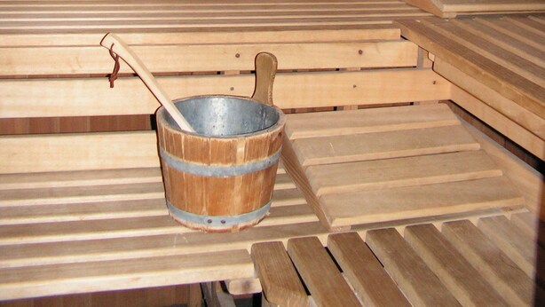 Uma sauna com bancos de madeira e um balde de metal.