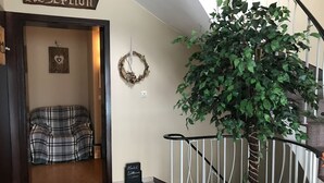 Uma área de recepção com uma placa, uma guirlanda, um banco e uma escada.