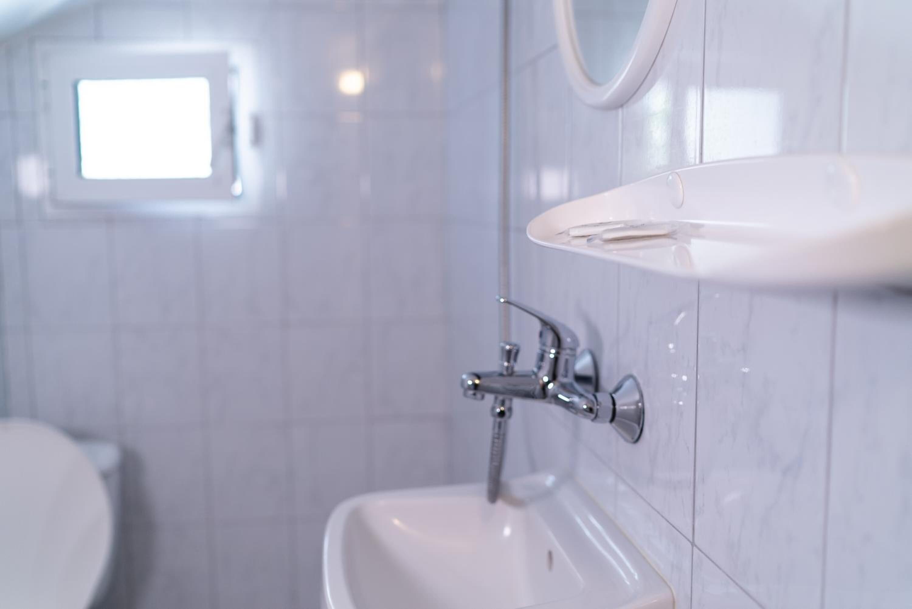 A bathroom with a white sink, a mirror, and a window.