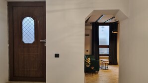 A hallway leading to a room with a wooden door, a small window, and a view of a room with a bed and a table. - Guest Rooms Plovdiv (Plovdiv)