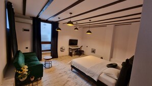 A modern bedroom with a bed, a desk, a chair, and a green armchair. - Guest Rooms Plovdiv (Plovdiv)