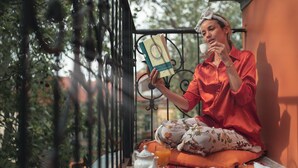 A person sitting on a balcony with a book, a teapot, and a glass of orange juice. - Guest Rooms Plovdiv (Plovdiv)
