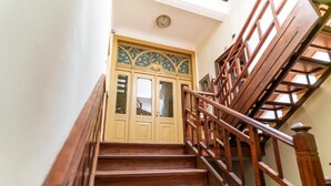 A wooden staircase with a handrail leading to a door with stained glass panels. - Guest Rooms Plovdiv (Plovdiv)