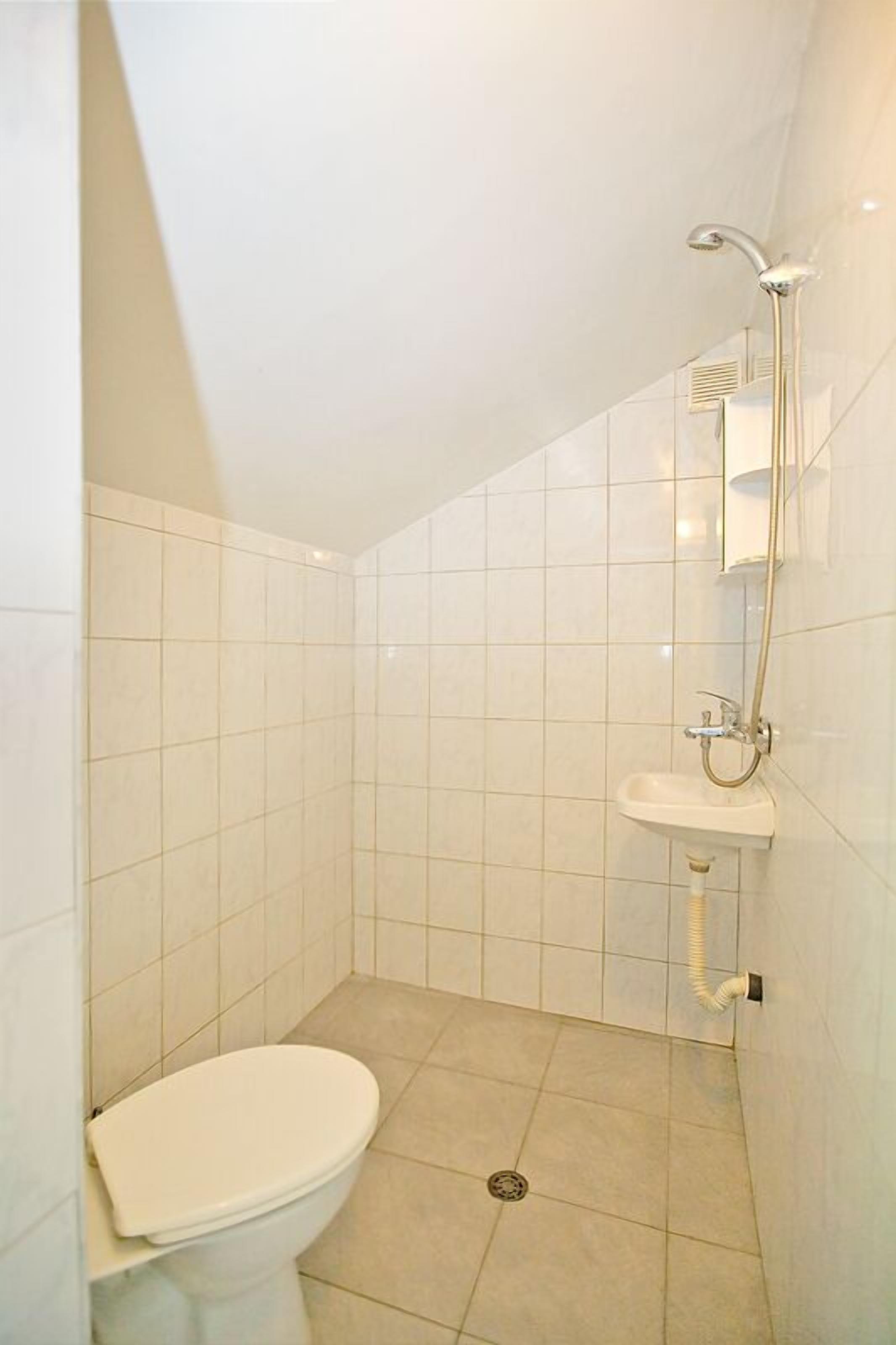 Een kleine badkamer met tegels, een toilet, een wastafel en een douche.