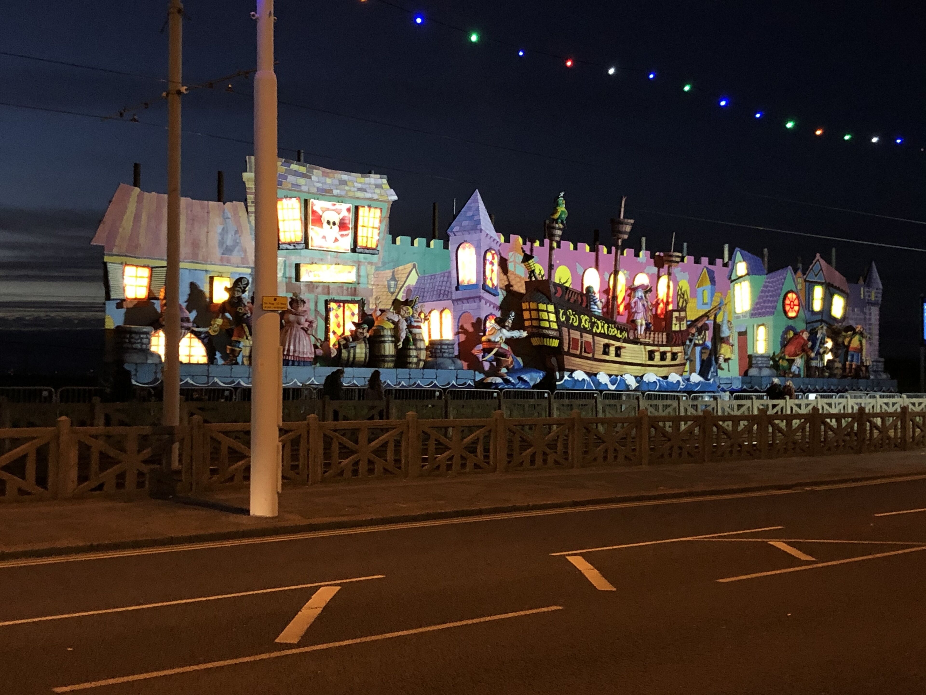 A brightly lit building with multiple levels and a variety of architectural styles, including a castle-like structure and a ship.