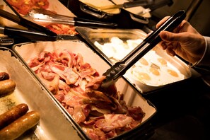 A buffet with various food items including bacon, sausages, and eggs. - Patterdale Hotel (Penrith)