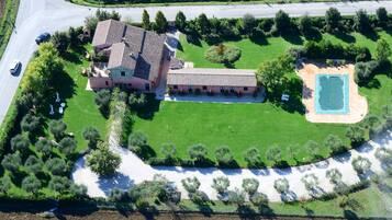 An aerial view of a large estate with a main house, a swimming pool, and a well-maintained lawn.