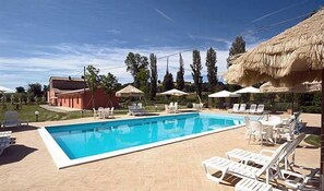 Una piscina al aire libre, sombrillas, sillones reclinables de piscina