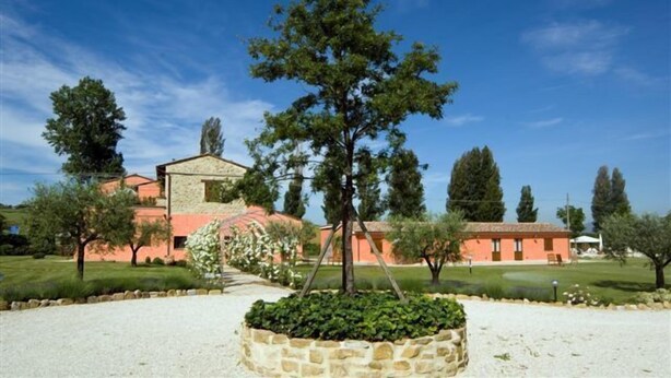 A building with a stone facade, a well-maintained lawn, and a clear blue sky. - Casale Le Selvette (Perugia)