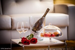 En flaska champagne, två vinglas och ett fat med efterrätter står på ett bord i vardagsrummet.