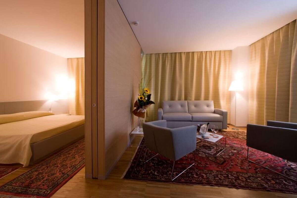 A hotel room with a bed, a sofa, a chair, and a coffee table.