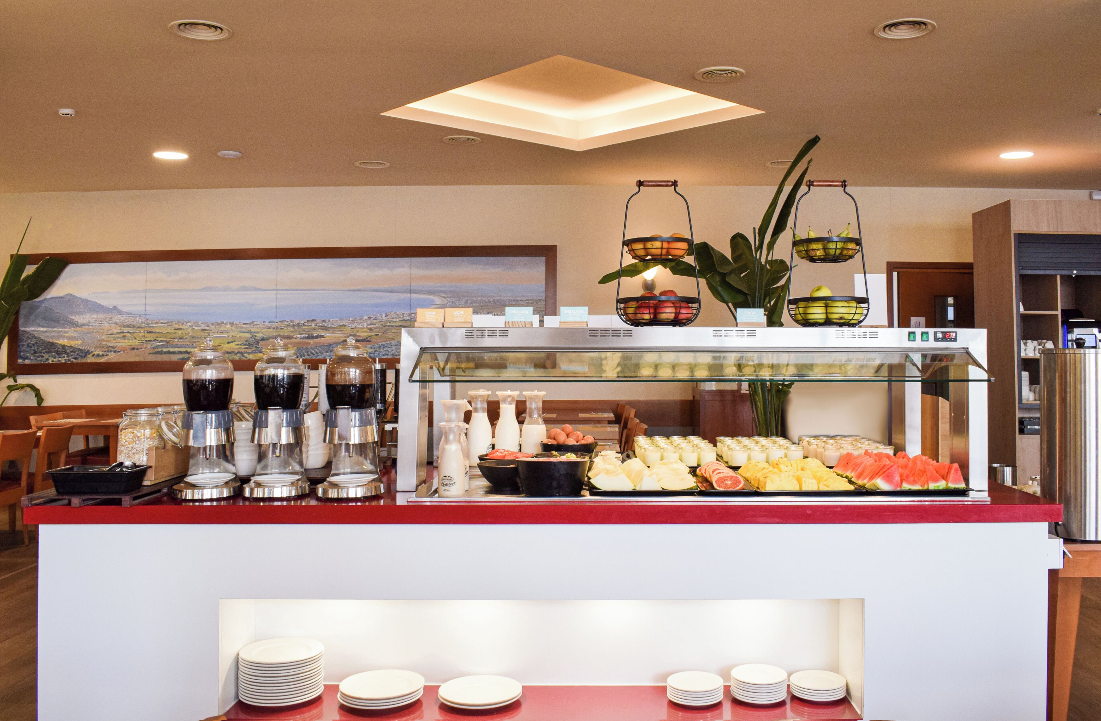Uma área de buffet com diversas opções de comida, incluindo frutas, queijos e bebidas.