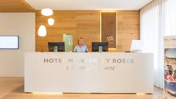 A reception desk with a sign reading "HOTEL MONTERREY ROSES by Pierre & Vacances".