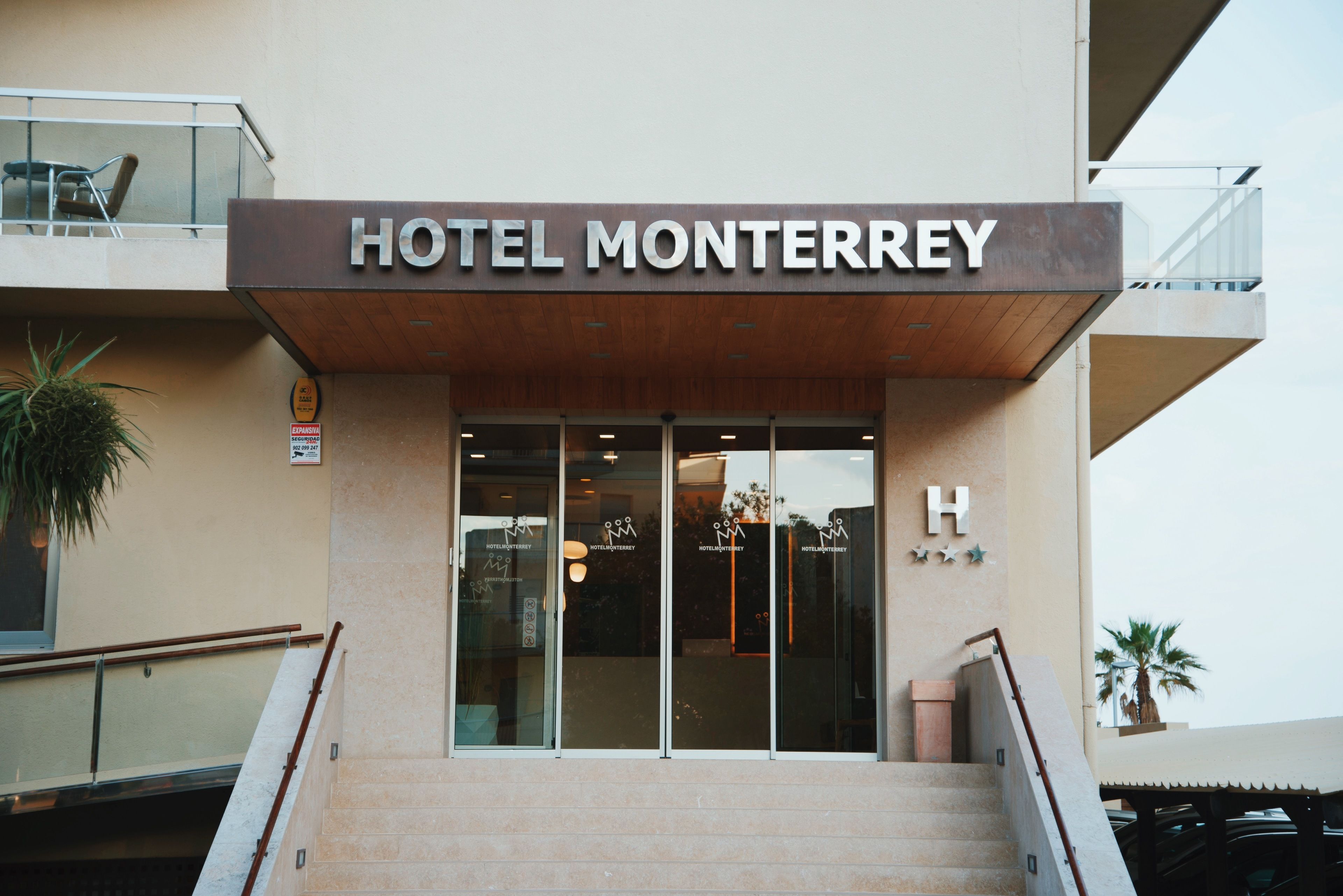 The entrance of Hotel Monterrey with a modern facade, glass doors, and a visible 'H' sign indicating the hotel.
