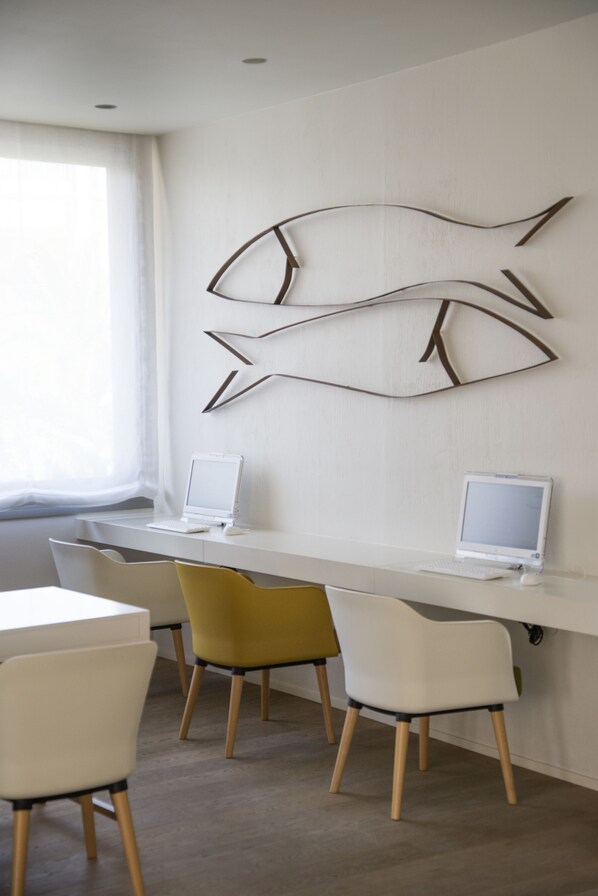 A modern office space with two desks, each with a laptop, and three chairs with wooden legs. - Hotel Monterrey Roses by Pierre & Vacances (Roses)