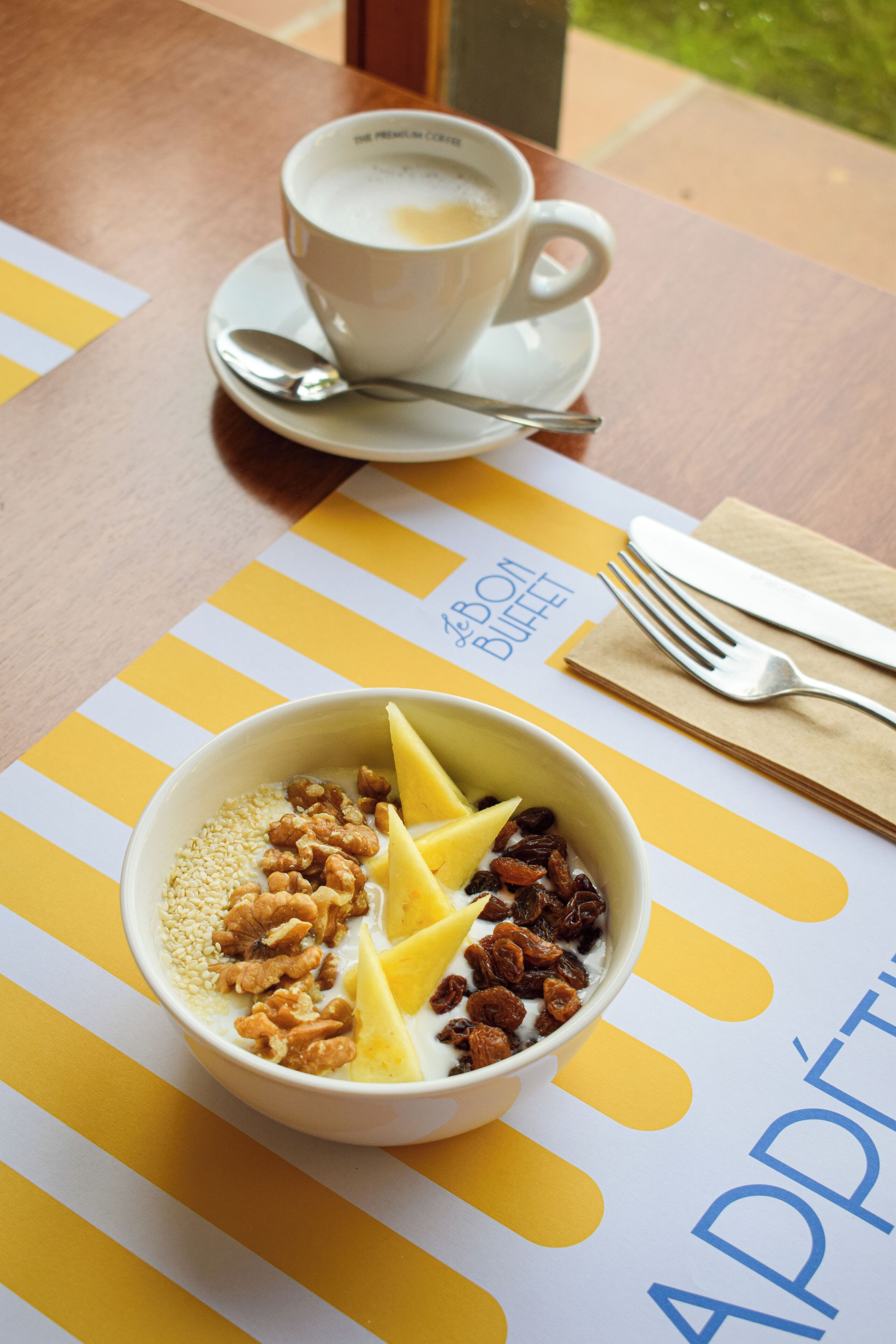 A bowl of cereal with fruits and nuts on a table with a striped placemat.
