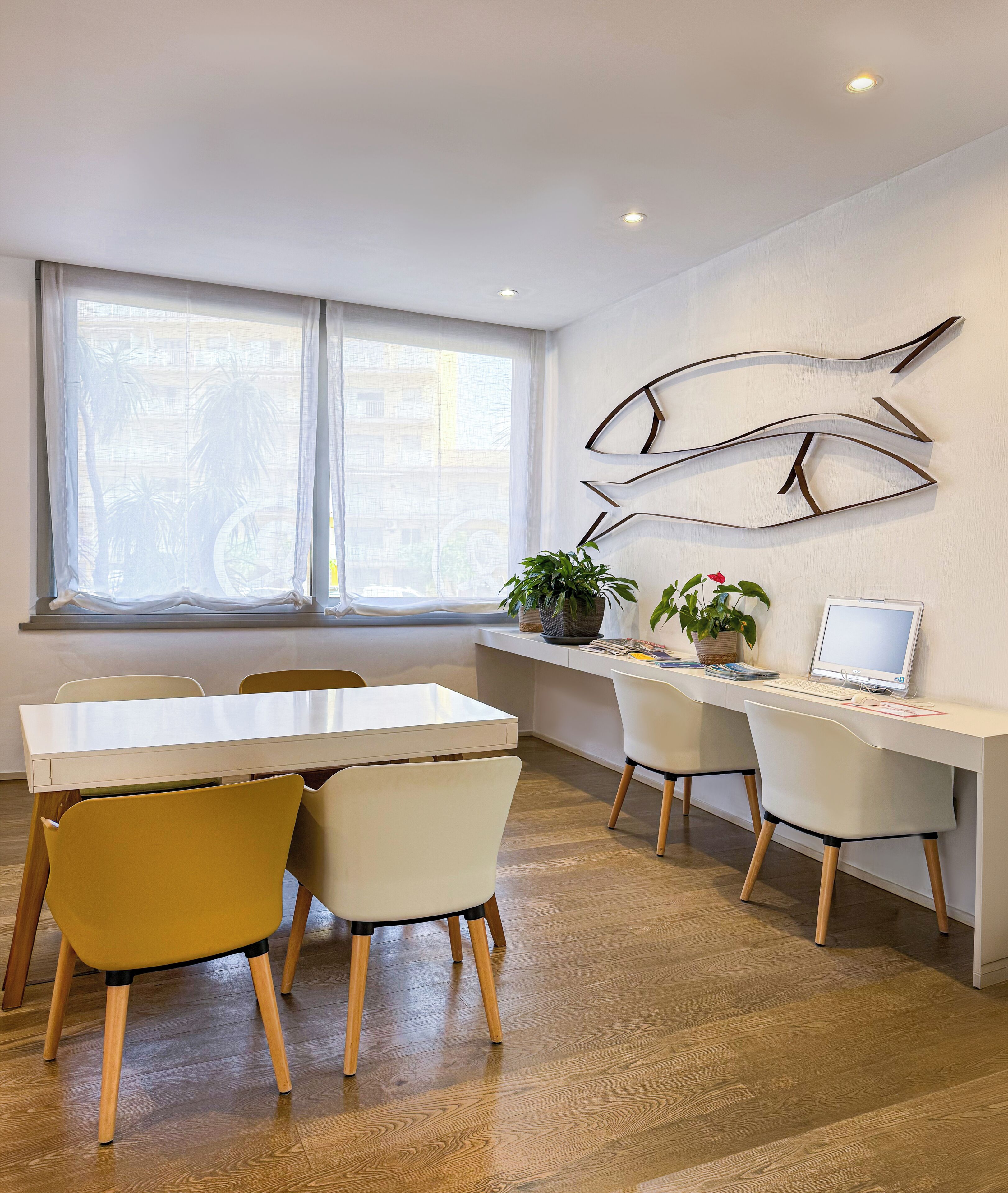 Un espacio de oficina moderno con un escritorio blanco, dos sillas, una computadora y arte decorativo en la pared.