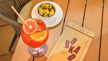 A table with a glass of drink, a bowl of olives, and a menu.