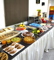 Un bufé con diversas opciones de comida, como frutas, bollería y bebidas.