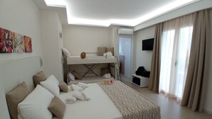 Habitación de hotel con una cama litera, un escritorio, un televisor de pantalla plana y un ventanal con cortinas.