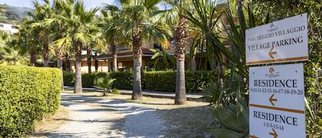 A sign indicating 'Parcheggio Villaggio Village Parking' and 'Residence' with directional arrows.