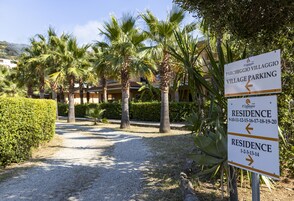 Señal que indica 'Parcheggio Villaggio Village Parking' y 'Residence' con flechas direccionales.