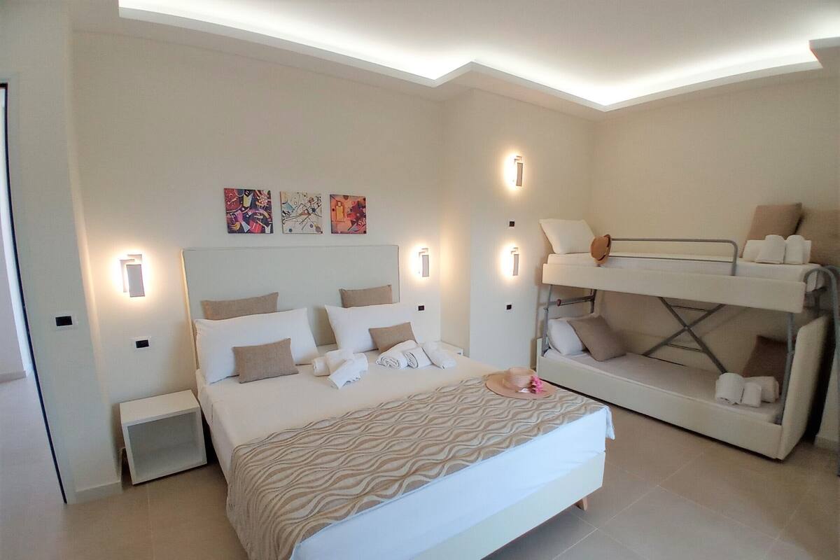 A modern bedroom with a large bed, a bunk bed, and artwork on the walls.