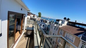 Ein Balkon mit Blick auf das Meer, eine Glastür und ein kleiner Tisch mit Stühlen.