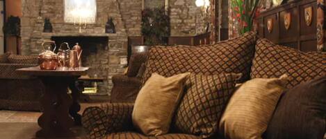 A cozy living room with a patterned sofa, a fireplace, and a stone wall.
