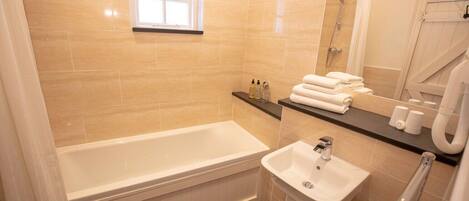 Un baño con bañera, lavamanos, ventana y ducha.