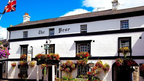 Un edificio bianco con la scritta "The Bear" sulla facciata, caratterizzato da numerose finestre e cesti di fiori.