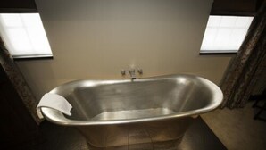 Un bagno moderno con una vasca freestanding, un asciugamano e una finestra con tende.