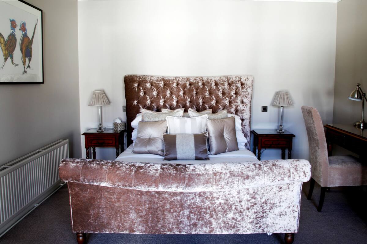 A bedroom with a large bed, two bedside tables, a chair, and a desk.