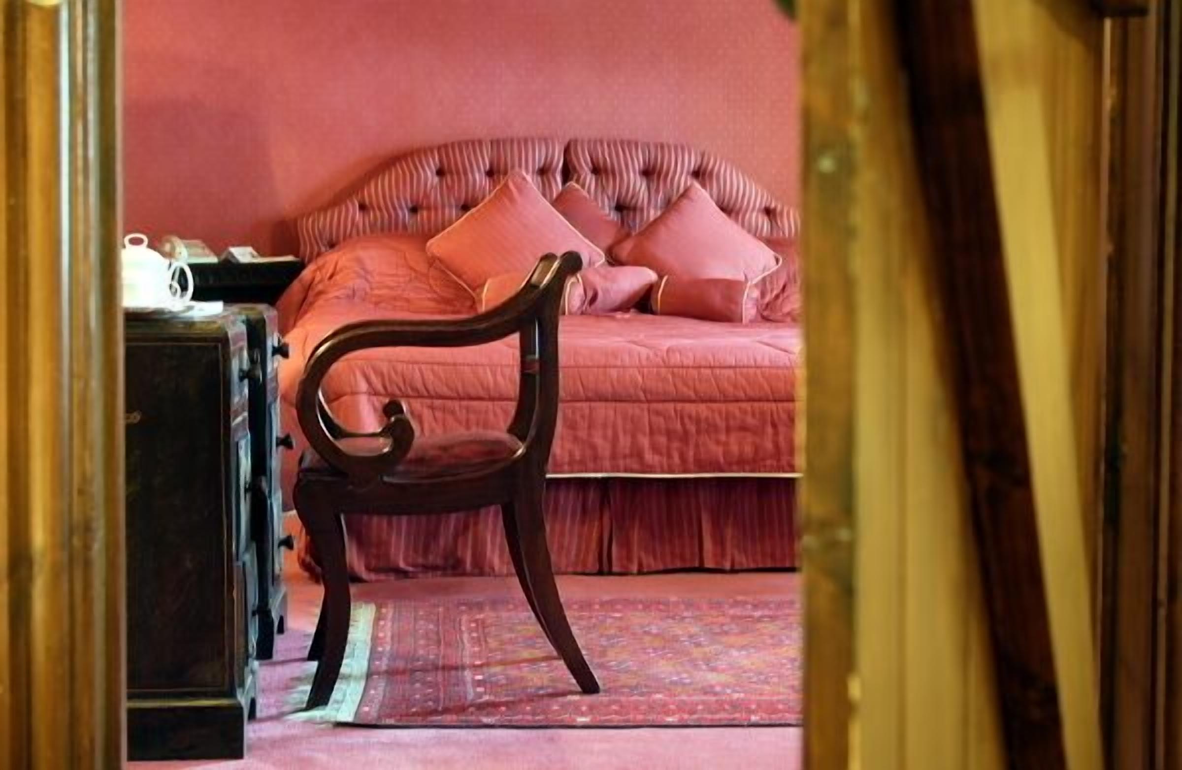 A bedroom with a bed, a chair, and a nightstand.