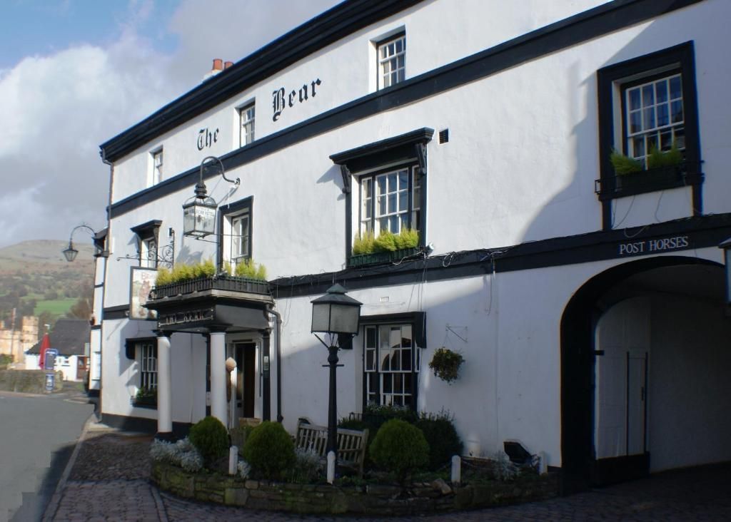 A traditional pub with a white facade, a sign reading 'The Bear,' and a section labeled 'Post Horses.'
